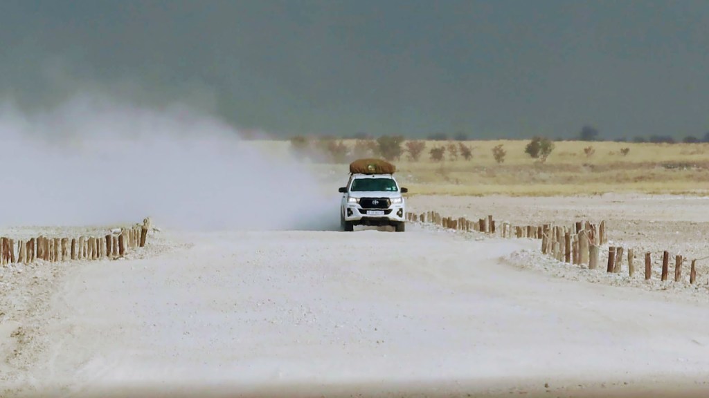 A 4x4 car driving on a gravel road in Namibia