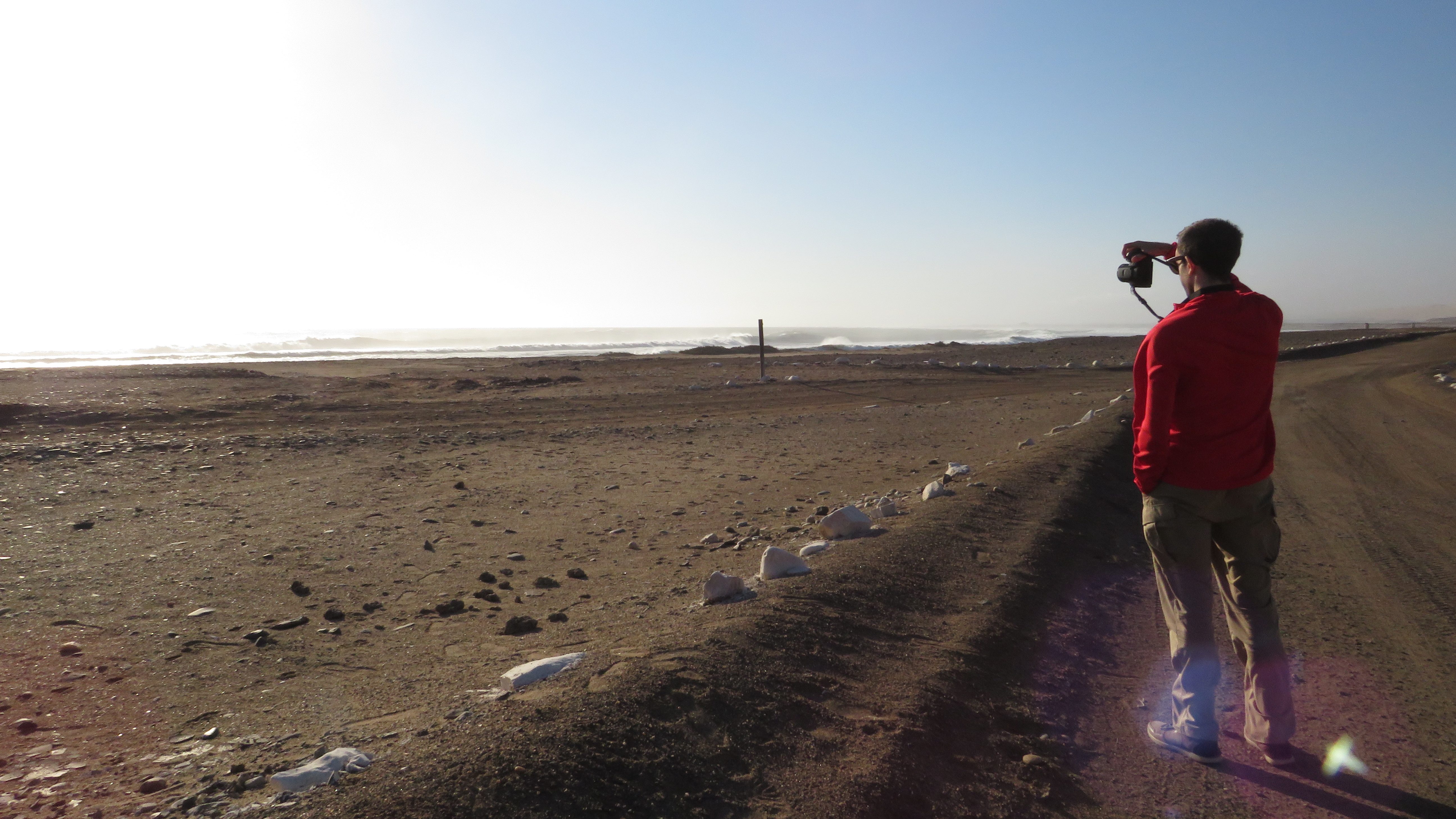 Man taking photo on empty beach in Skeleton Coast