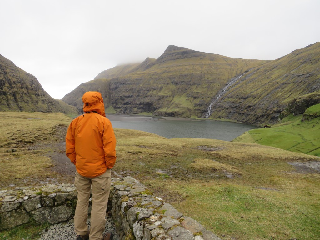 Man in rain jacket hiking landscape green