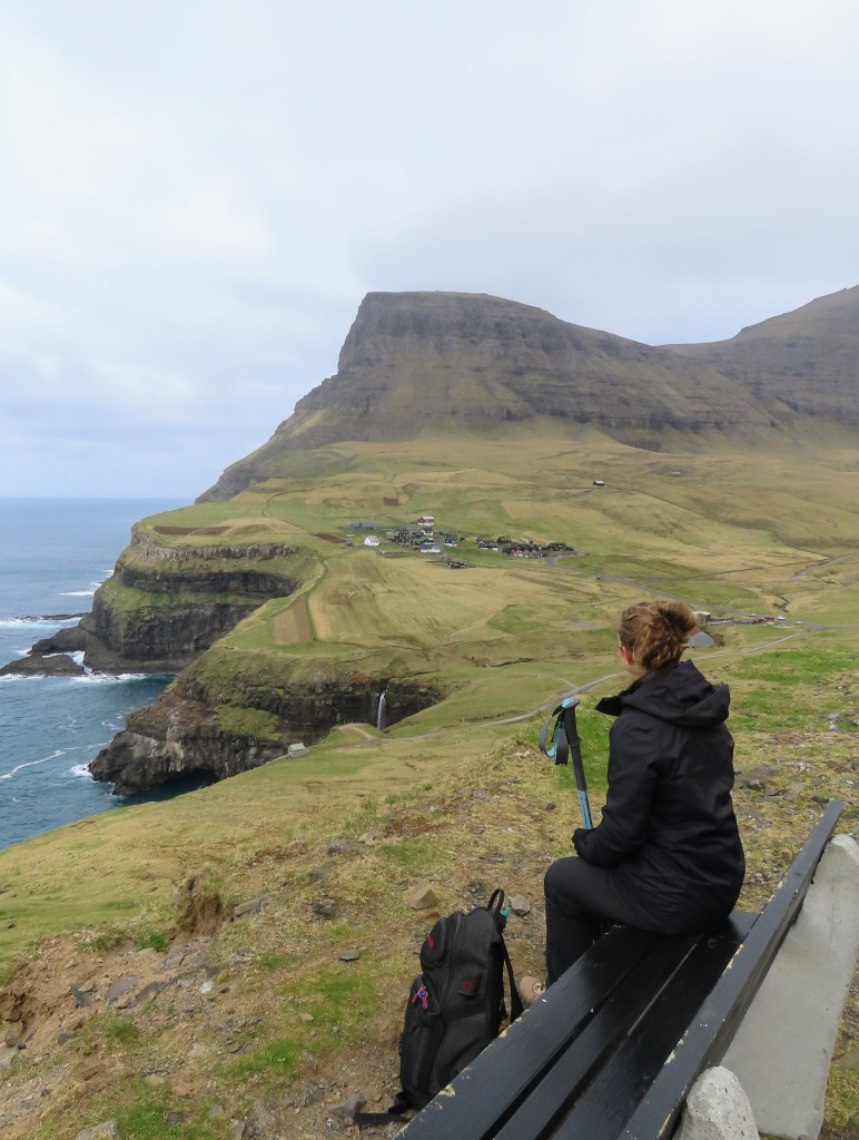 Girl sits on a bench and looks at a waterfall in the distance